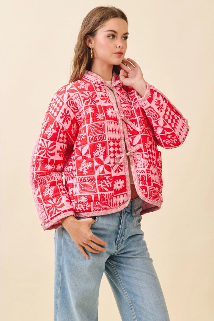 Woman wearing a red patterned jacket and blue jeans on a beige background