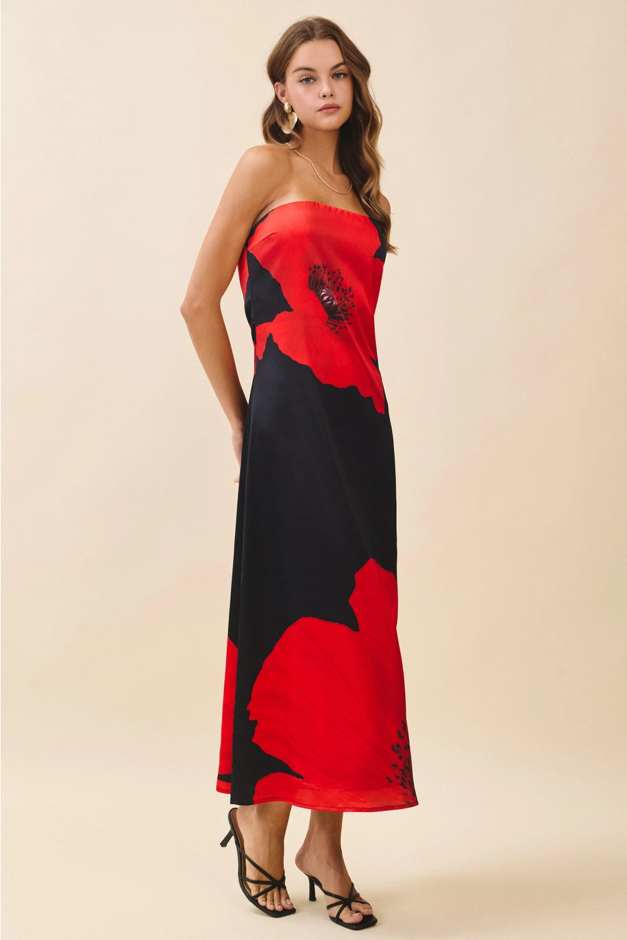 Woman wearing a strapless dress with red and black floral pattern on a beige background