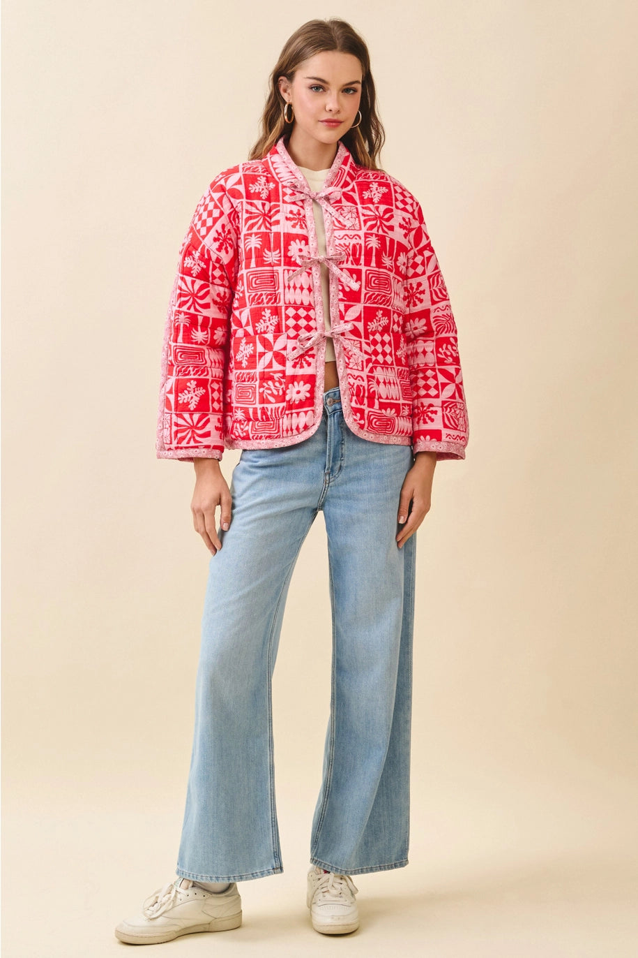 Woman wearing a red patterned jacket and light blue jeans on a beige background