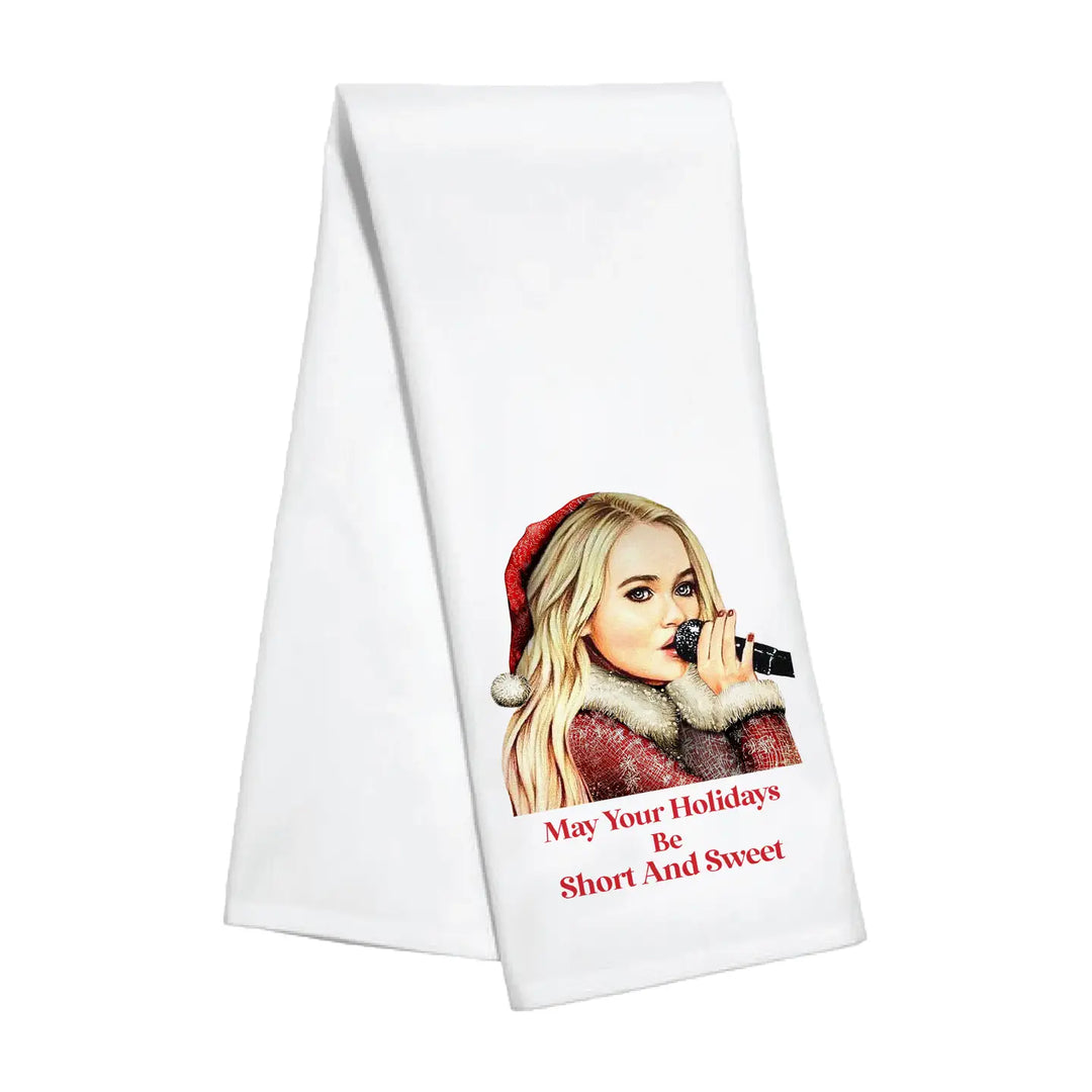White towel with a printed design of sabrina carpenter wearing a Santa hat and text " may your holidays be short and sweet'