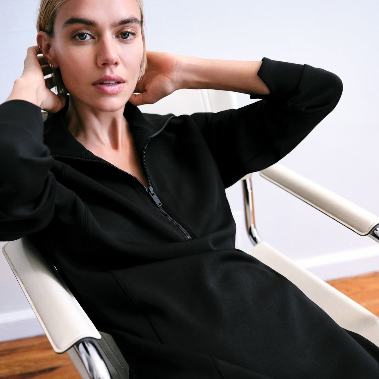 Woman lounging in a chair in a Spanx black dress 