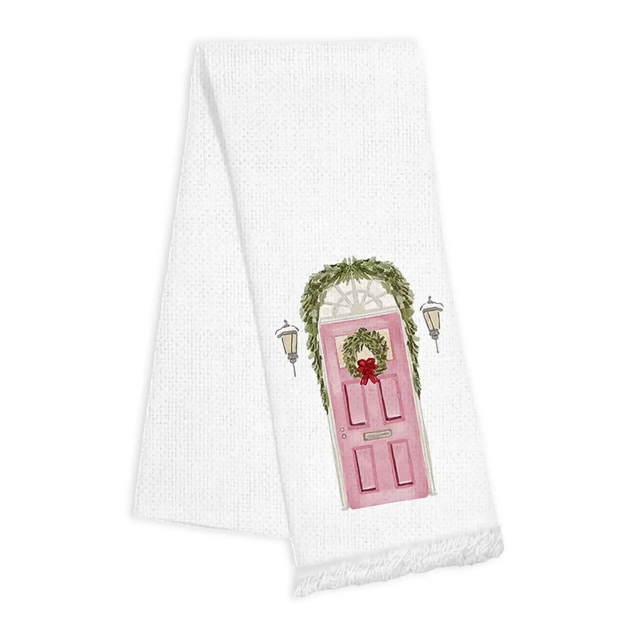 White towel with a pink door and wreath design and fringe detail