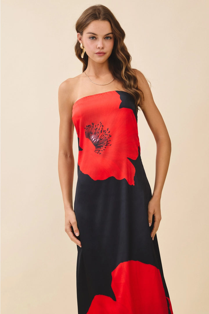 Woman wearing a strapless dress with red and black floral patterns on a beige background